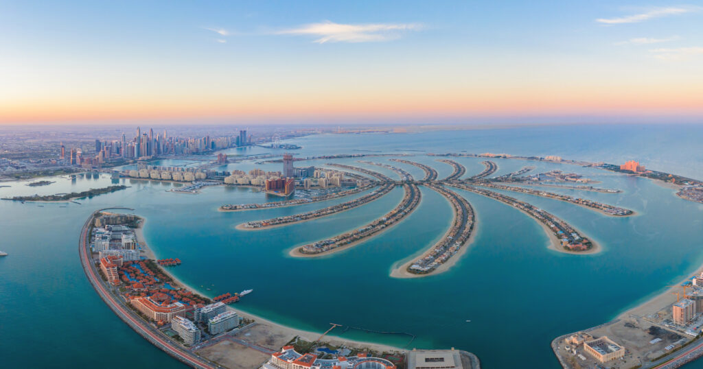 Aerial view of The Palm Jumeirah Island, Dubai Downtown skyline, United Arab Emirates or UAE. Financial district and business area in smart urban city. Skyscraper and high-rise buildings at sunset.